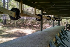 A row of seats under the wooden roof of the outdoor shooting range.
