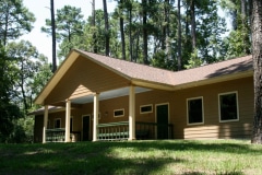A building with a covered porch in the woods.