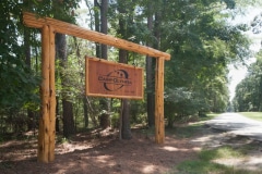 Large hanging wooden sign marks the entrance to the Outdoor Education Center at Camp Olympia.