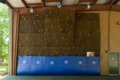 Wide angle view of an indoor climbing wall and safety mats.